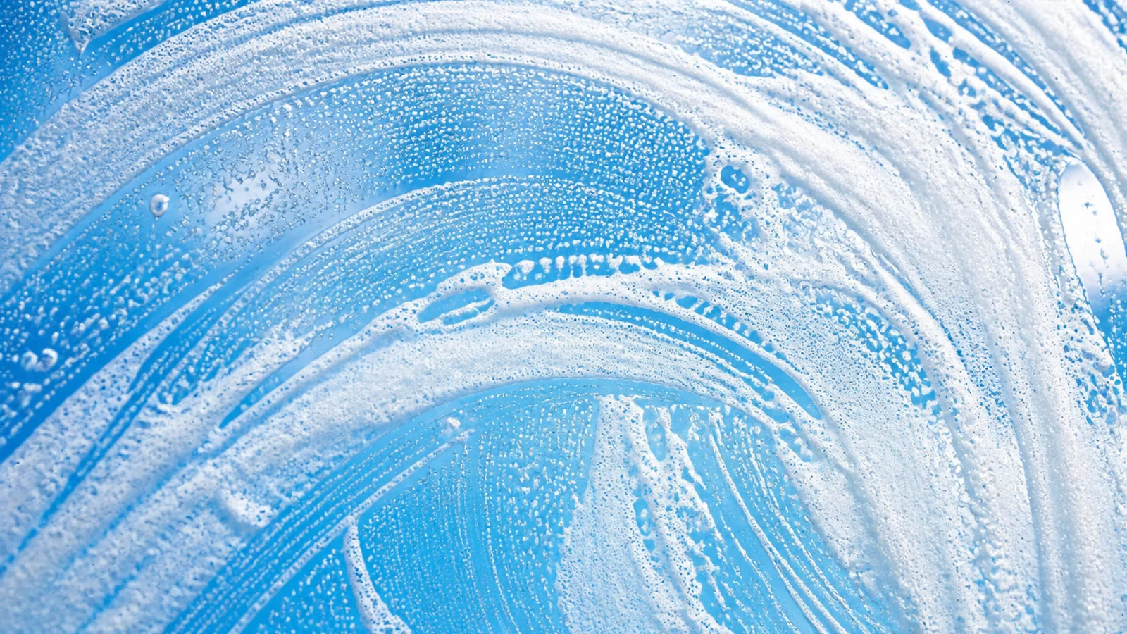 Fresh cleaning foam on blue glass for Bright Home Care property maintenance services